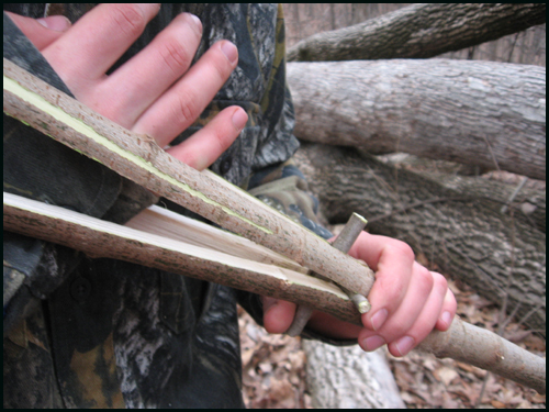 Work Em' In! One at a time, slide the twigs as far up and close to the lashing as possible. You may have to pry the wood with your hand to make the twigs fit. The spear really starts coming to life here as the four sections spread out.